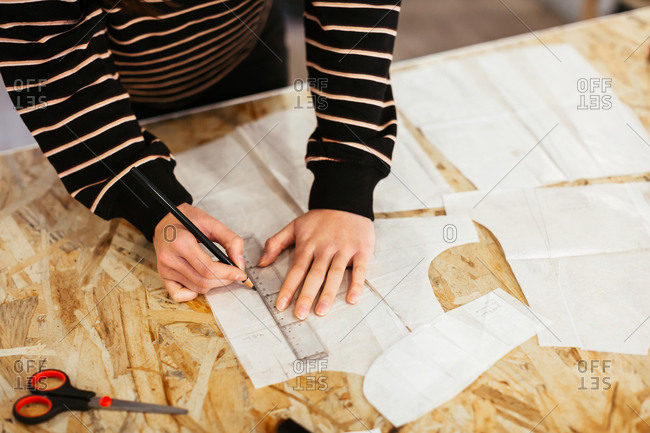 Anonymous designer working with sewing patterns in studio.