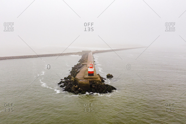 A pier with a light house at the end on the coast of the North Sea in the Netherlands