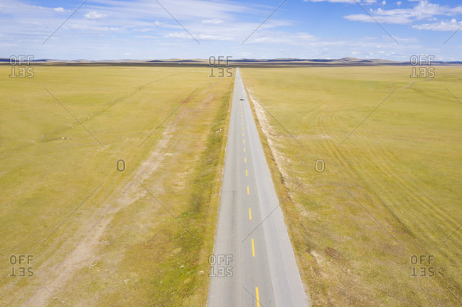 Single car on straight road to horizon in prairie