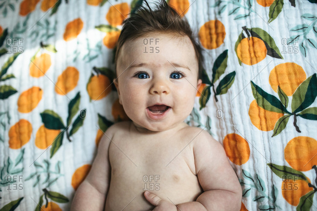Portrait of a happy blue eyed baby on a clementine blanket