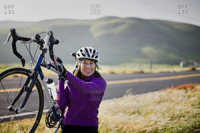 Mature woman lifting her bike in the air