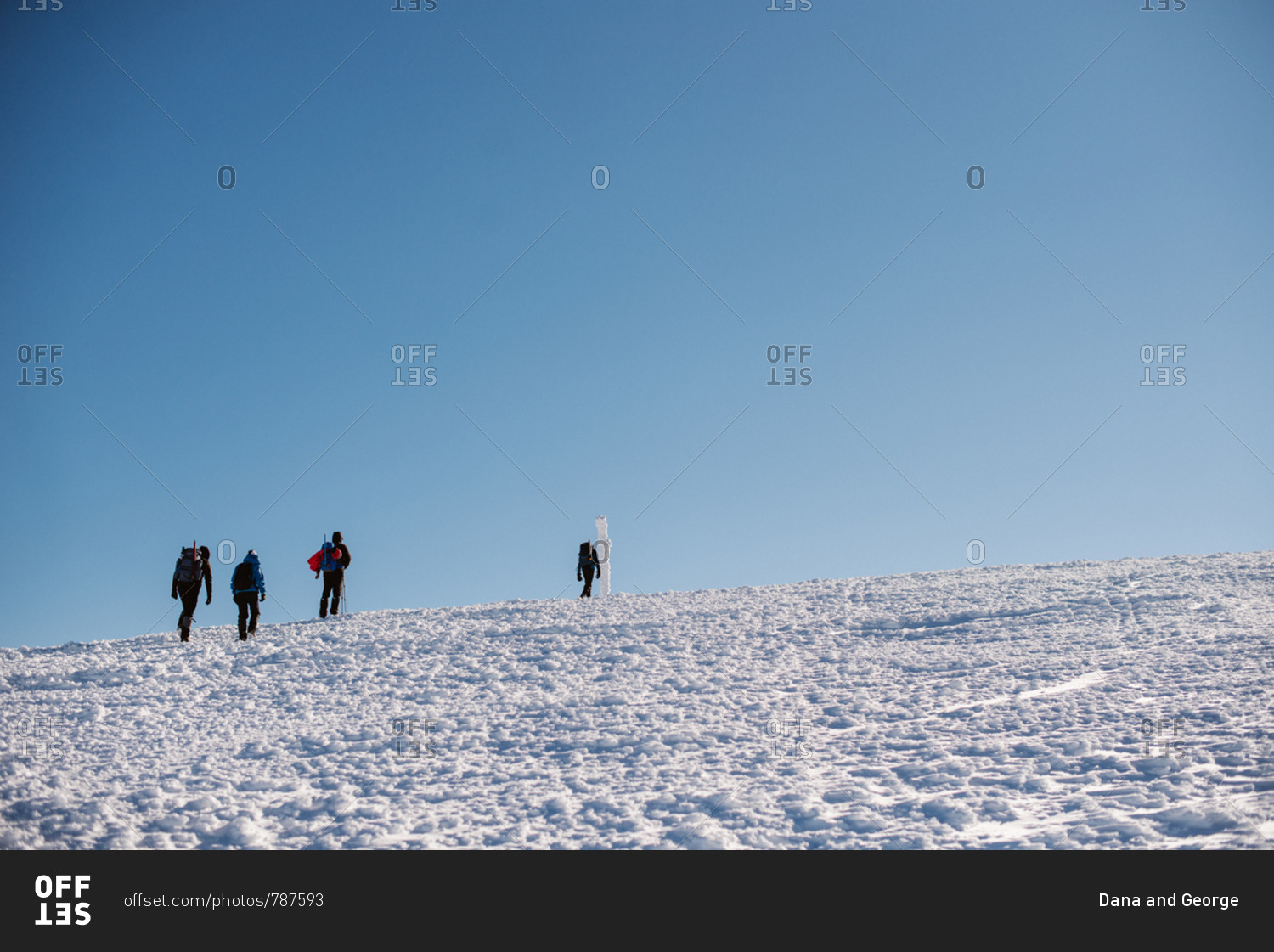 Low angle view of four people hiking on snowy hill