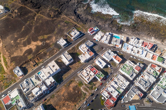Aerial view above of a coastal village in Canary island archipelago with traditional white houses, Tinajo, Spain.