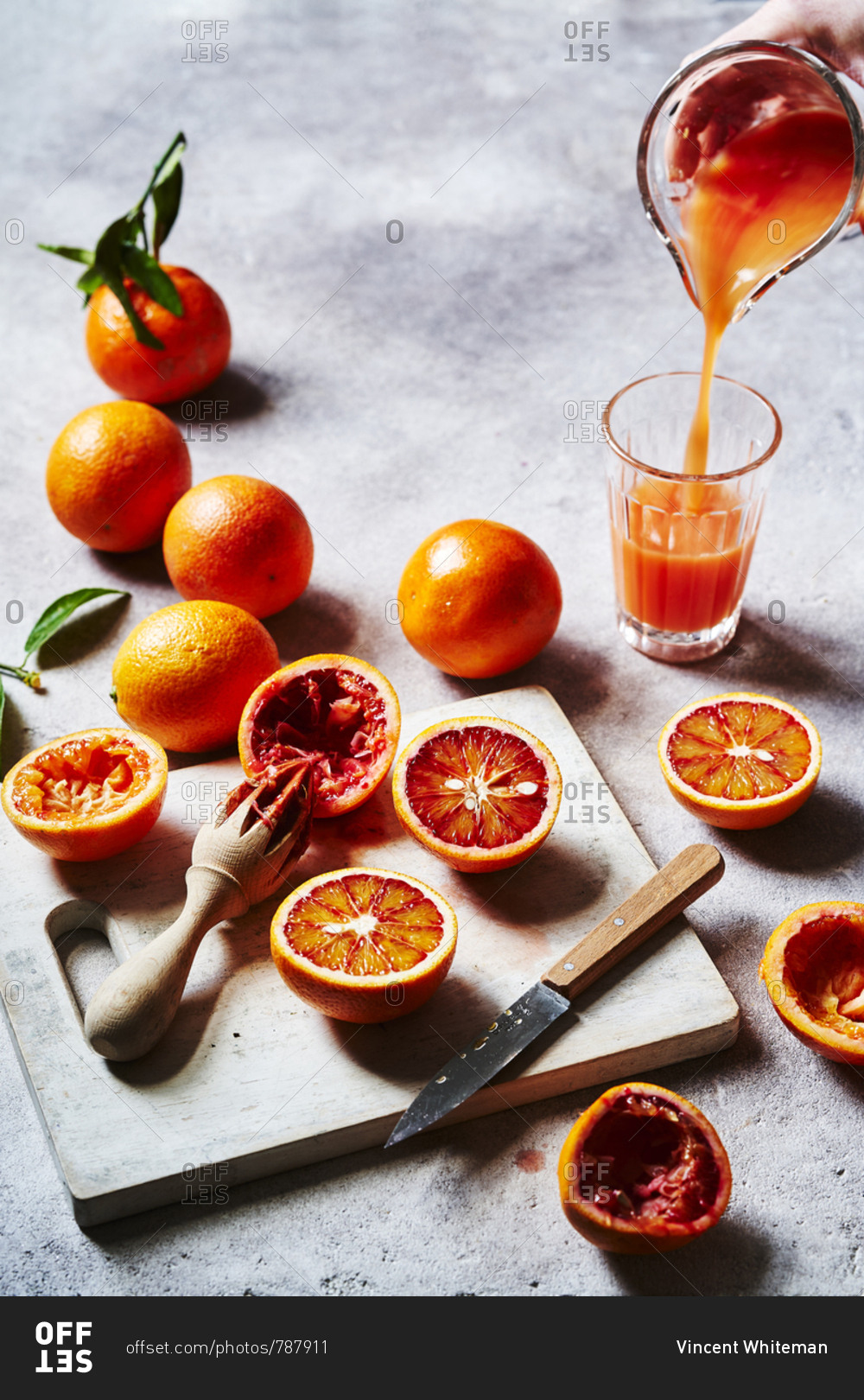 Blood oranges being cut up, squeezed into juice and poured, as a prep ...