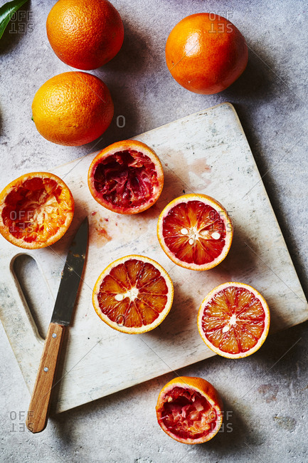 Blood oranges being cut up and squeezed into juice as a prep scene.