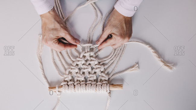 Detail shot of woman's hands weaving macrame in a private workshop.
