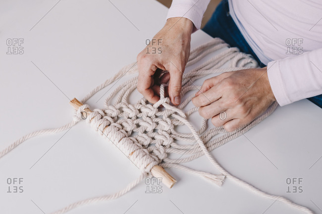 Detail shot of woman's hands weaving macrame in a private workshop.