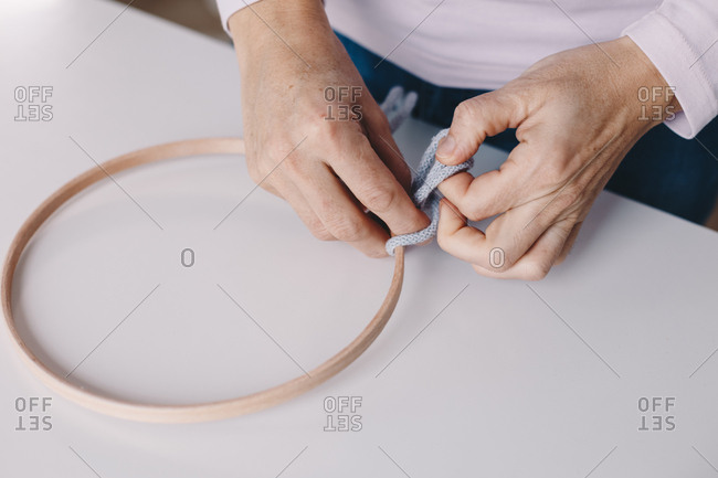Close up of female hands making a macrame on a dream catcher.