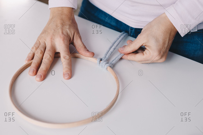 Detail shot of woman's hands making a macrame on a dream catcher.
