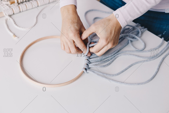 Close up of female hands making a wall hanging macrame.