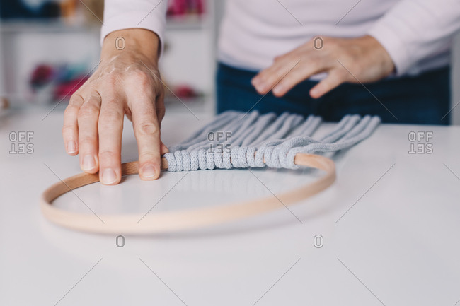 Close up of female hands putting a macrame on a dream catcher top.