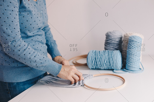 Close up of female hands making a macrame wall hanging dream catcher.