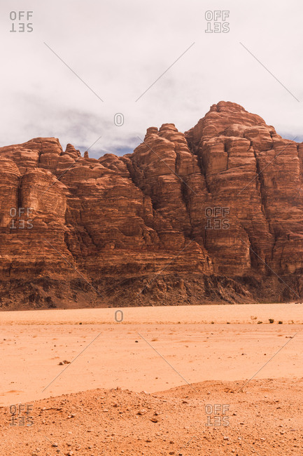 Landscape of majestic solid cliffs of sandstone rock in empty desert valley of Wadi Rum, Jordan