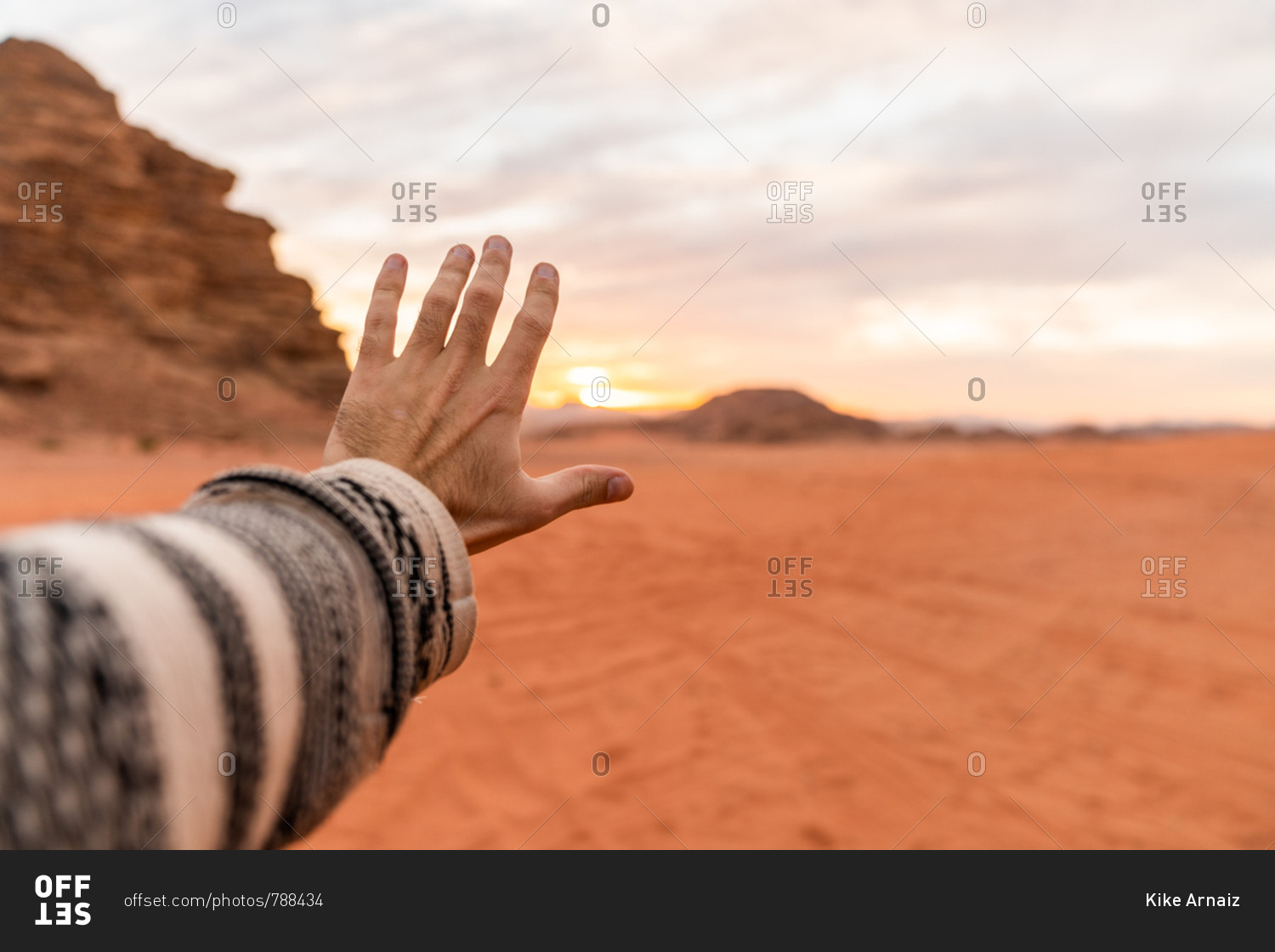 Crop male hand outstretched toward sunset sky in red desert valley of Wadi Rum, Jordan