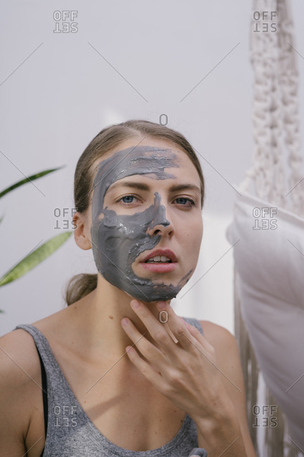 Young beautiful woman at home put on a beauty face mask