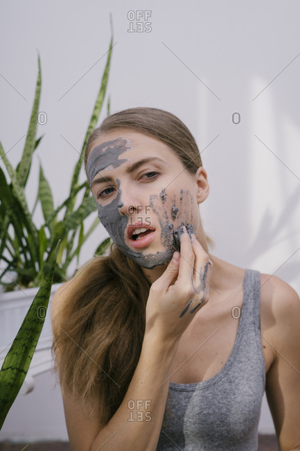 Young beautiful woman at home put on a beauty face mask