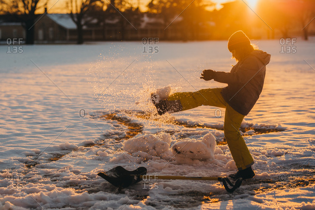 Boy kicks a ball of snow