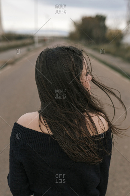 Portrait of the back of a young woman on a road with movement in her hair
