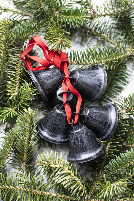 Black metal bells tied with red ribbon on twig of Christmas tree