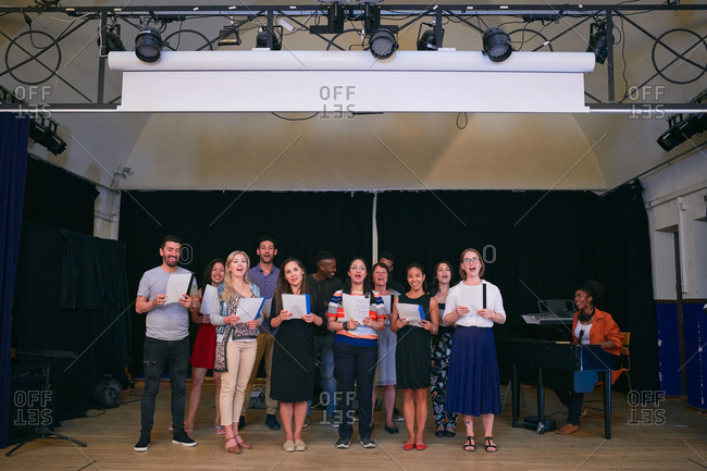 Choir members performing on stage in school auditorium