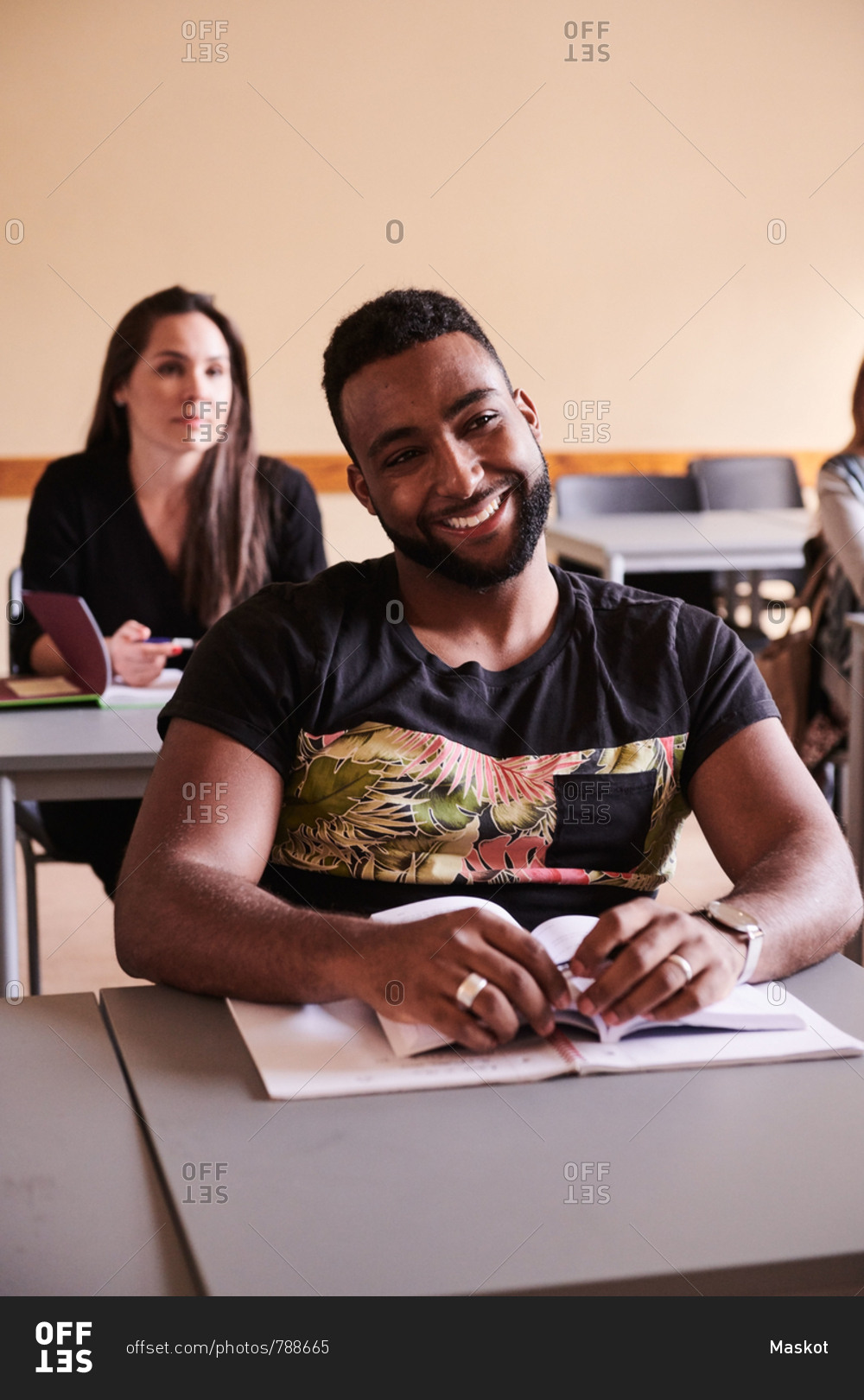 Confident student smiling while sitting at desk in language school