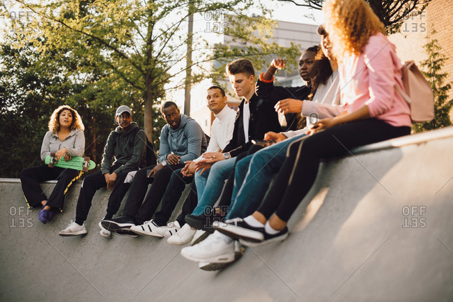 Multi-ethnic friends sitting at skateboard park