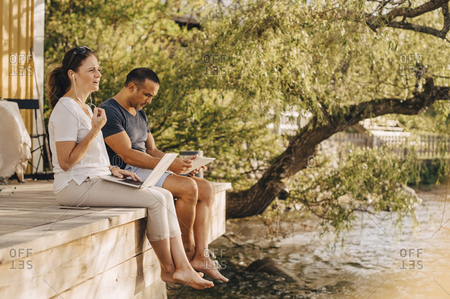 Mature couple using laptops while sitting at patio in holiday villa