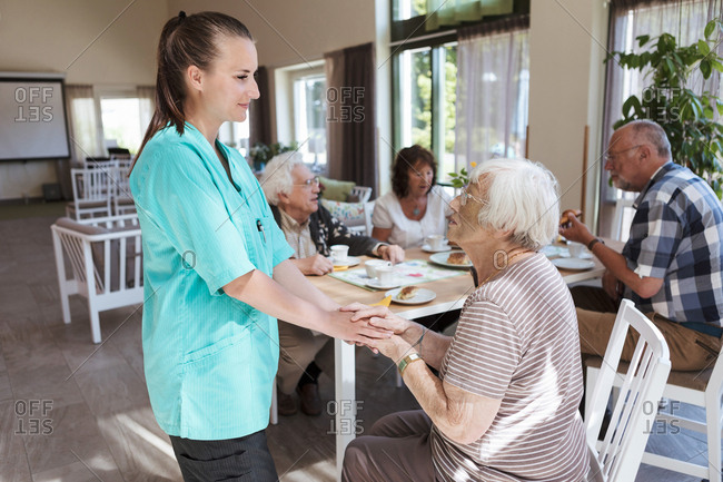 Nurse comforting senior woman while having breakfast at nursing home