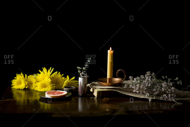 Beeswax candle with yellow flowers on a wooden table