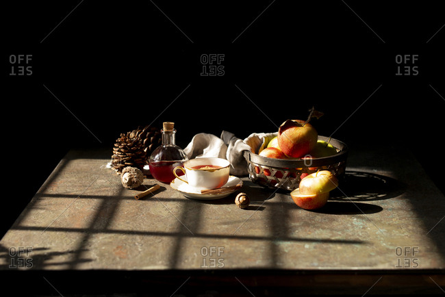 Apples inside a woven wood basket with a cup of tea in a sunny afternoon
