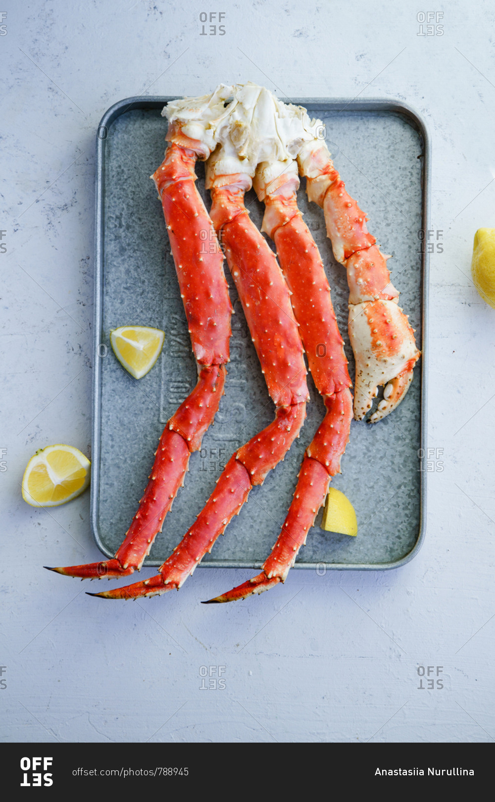 Cooked alaskan king crab legs with lemon on metallic tray