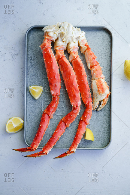 Cooked alaskan king crab legs with lemon on metallic tray