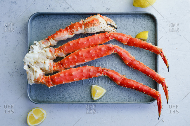 Cooked alaskan king crab legs with lemon on metallic tray