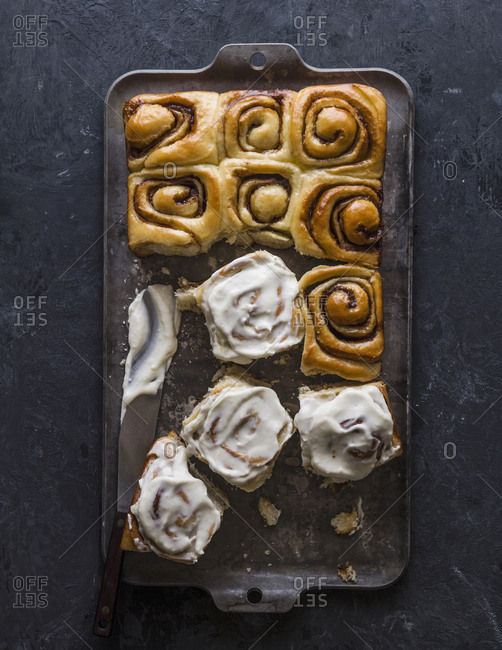 High angle view of cinnamon buns with cream in baking sheet on table