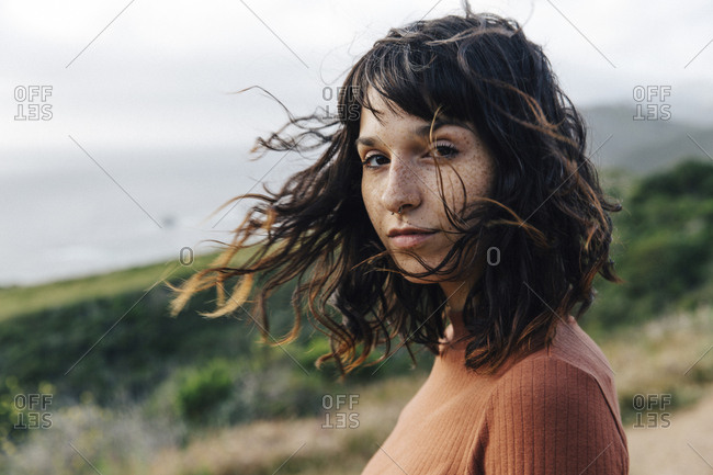 Portrait of confident woman with freckles standing against sky