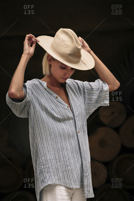 Confident woman wearing beige hat while standing against decorated wall