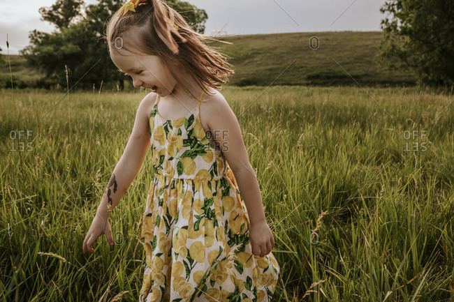 Happy cute girl looking down while standing on grassy field
