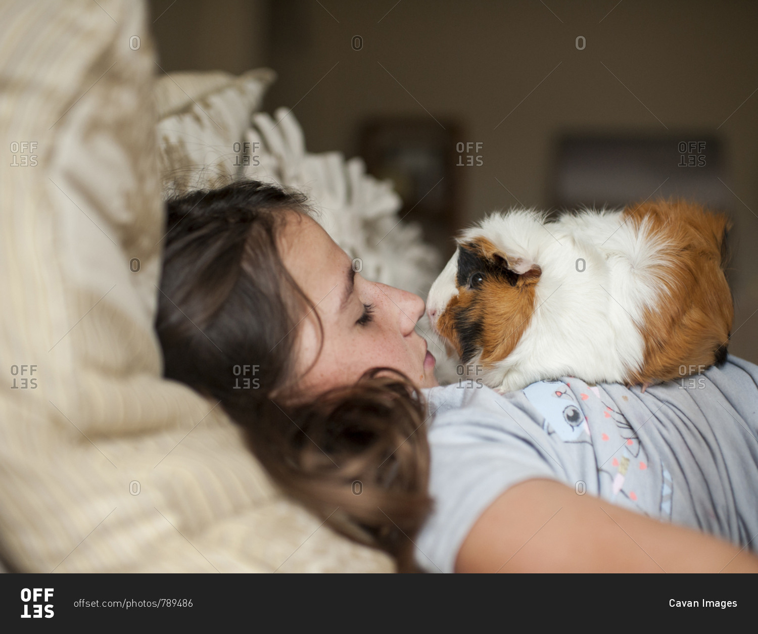 Side view of girl with guinea pig lying on bed at home