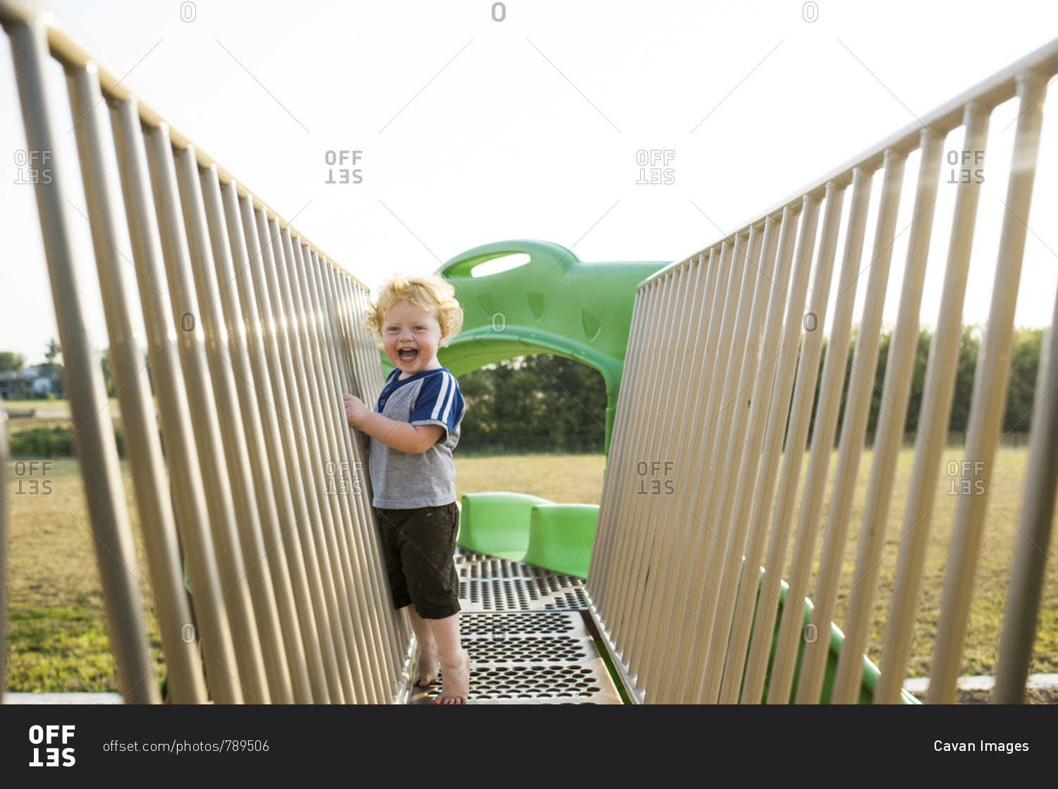 Portrait of cute cheerful baby boy playing on outdoor play equipment at playground