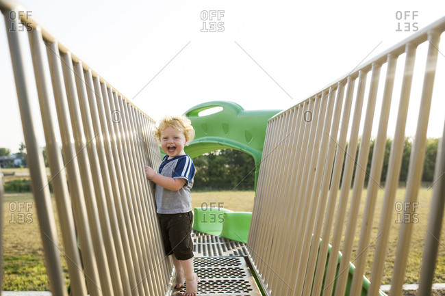 Portrait of cute cheerful baby boy playing on outdoor play equipment at playground