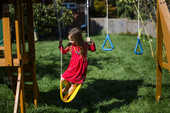 High angle view of playful girl standing on swing at playground during sunny day