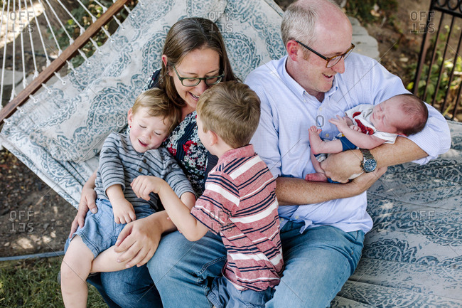 High angle view of happy playful family sitting on hammock at park