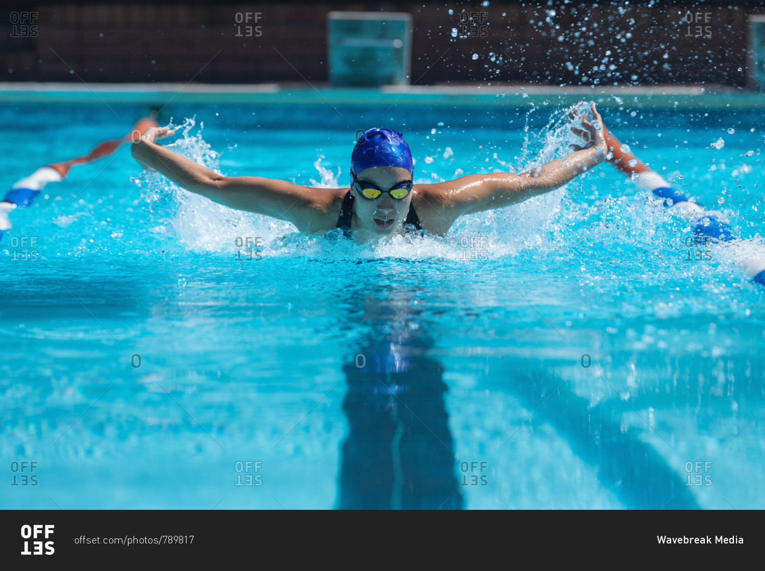 Front view of young female swimmer with swim goggle swimming at swimming pool