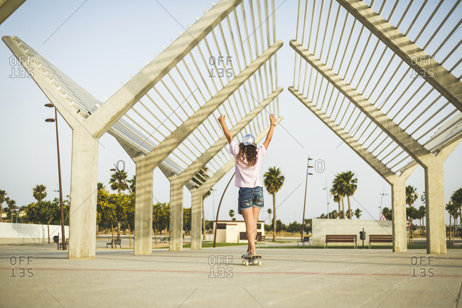 Girl on skateboard- raising arms- rear view