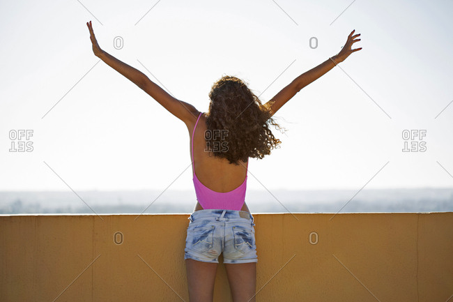 Portrait of teenage girl- raising arms- rear view
