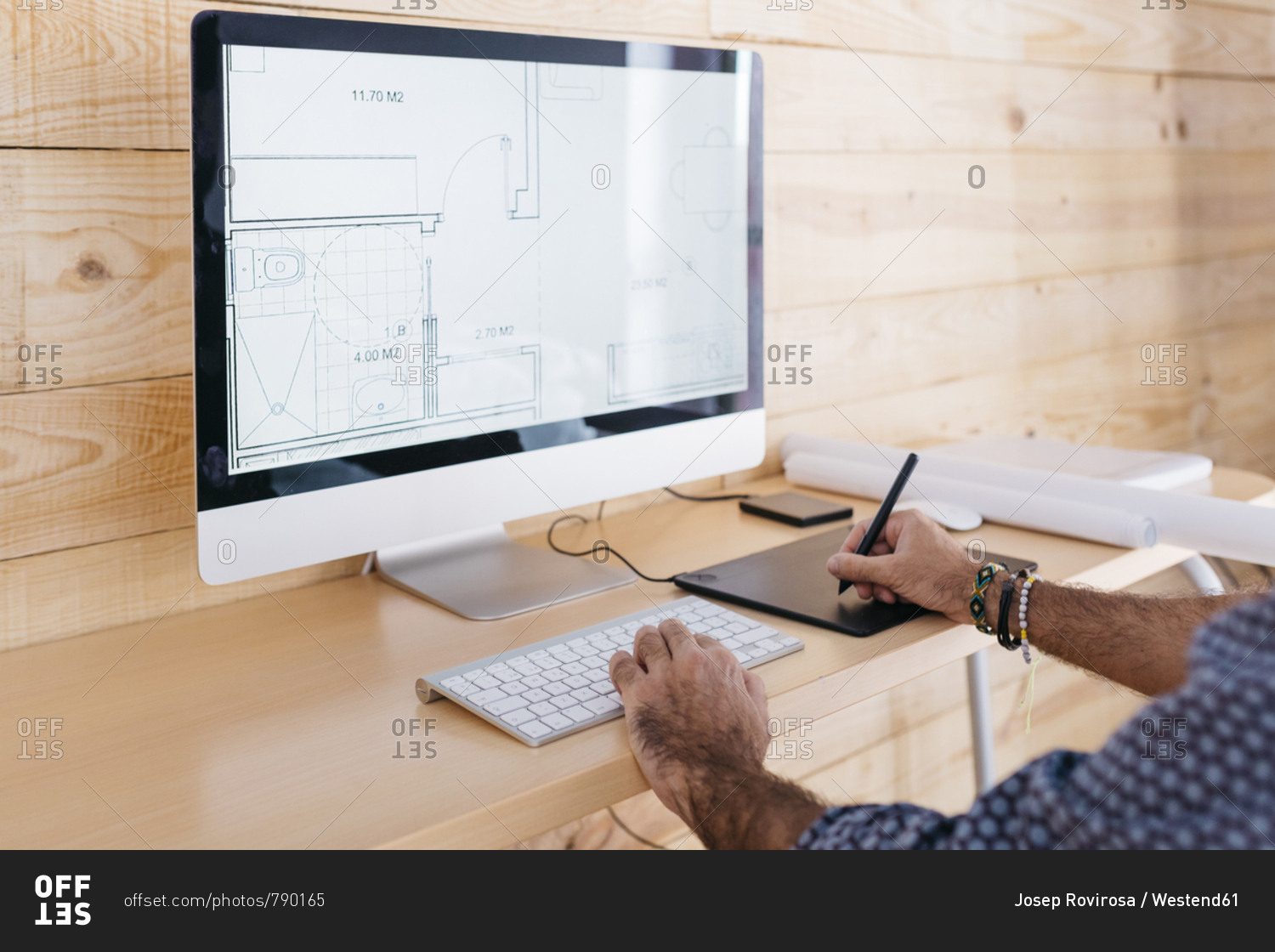 Close-up of man working on floor plan at home using the computer and graphics tablet