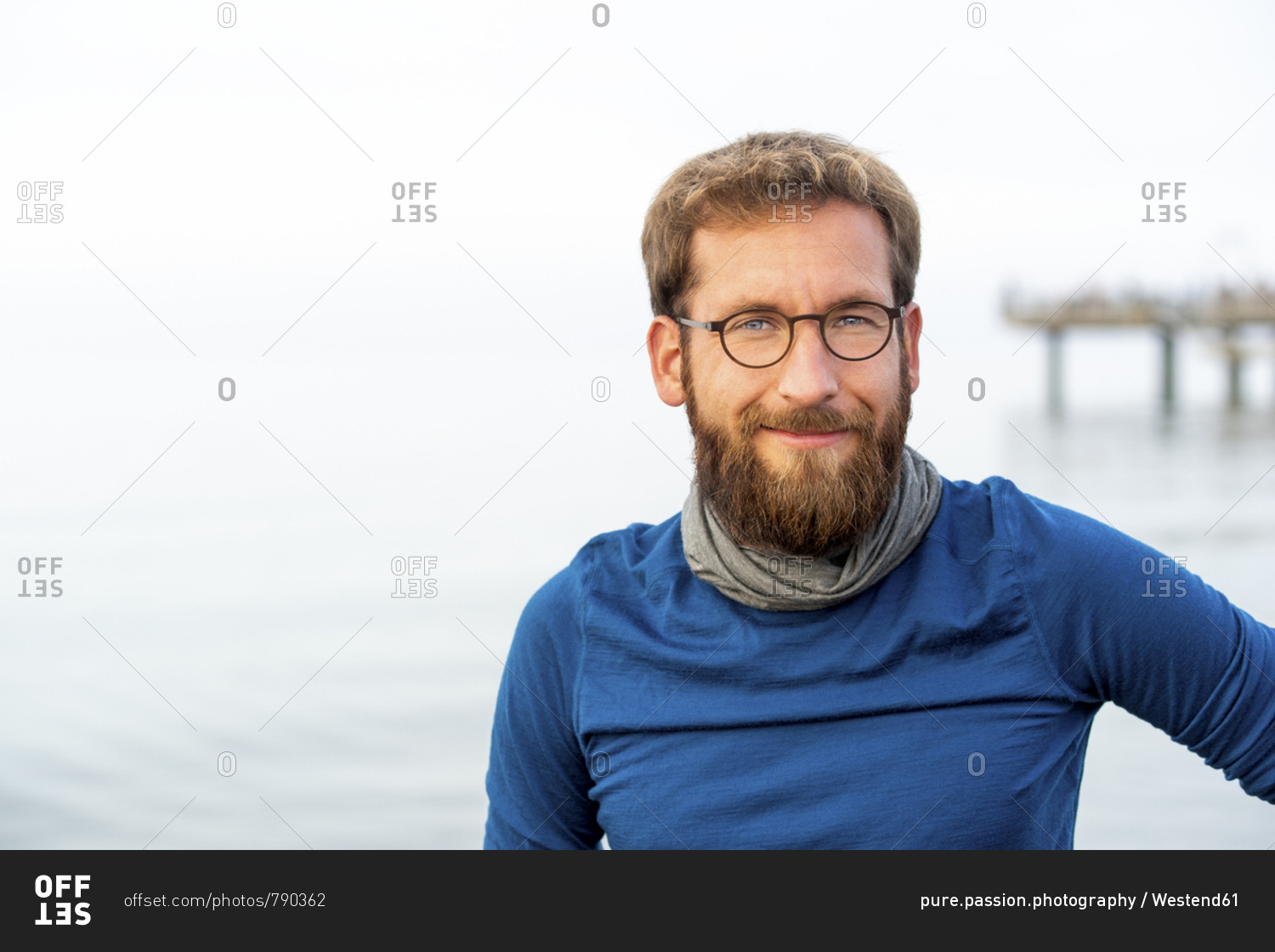 Germany- Rerik- portrait of bearded man in front of the sea wearing metal-rimmed spectacles