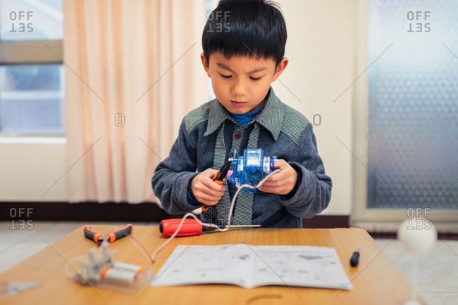 Little boy concentrate his attention on assembling robot carefully.