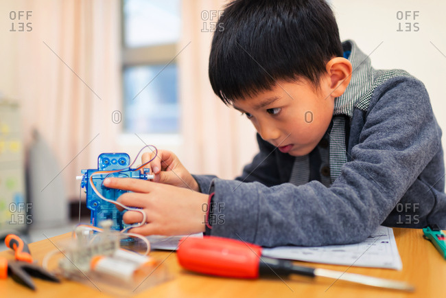 Little boy concentrate his attention on assembling robot carefully.