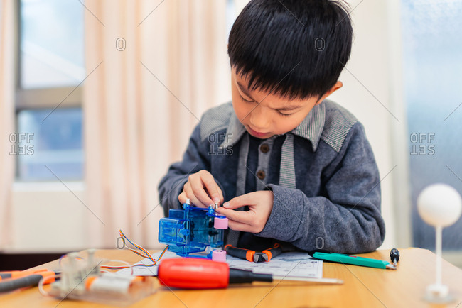 Little boy concentrate his attention on assembling robot carefully.